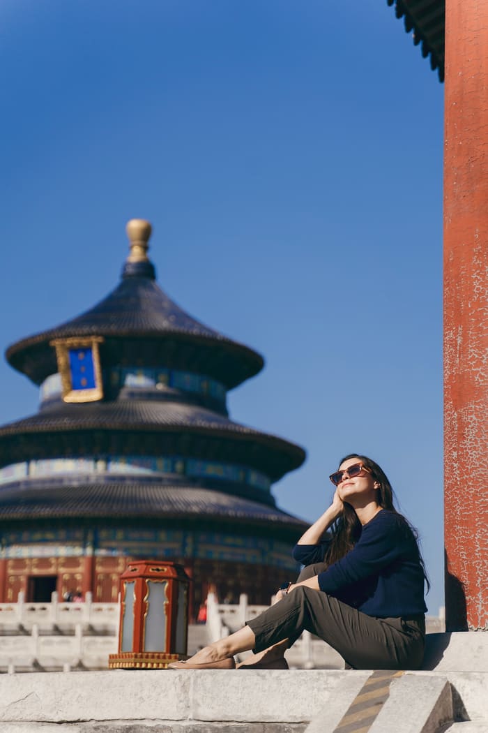 Mujer sentada de perfil, detrás destaca un templo tradicional de arquitectura china
