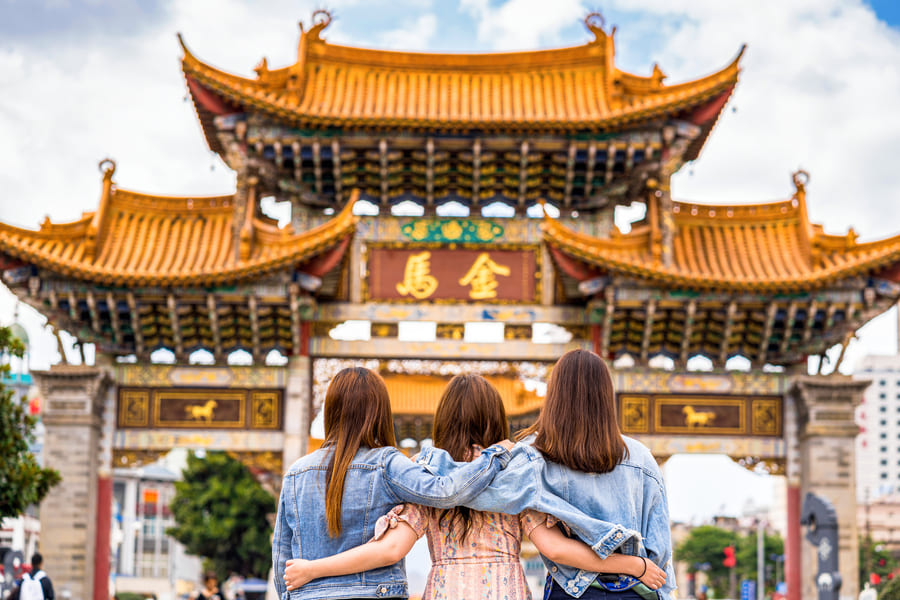 Tres mujeres abrazadas frente a una arquitectura tradicional China